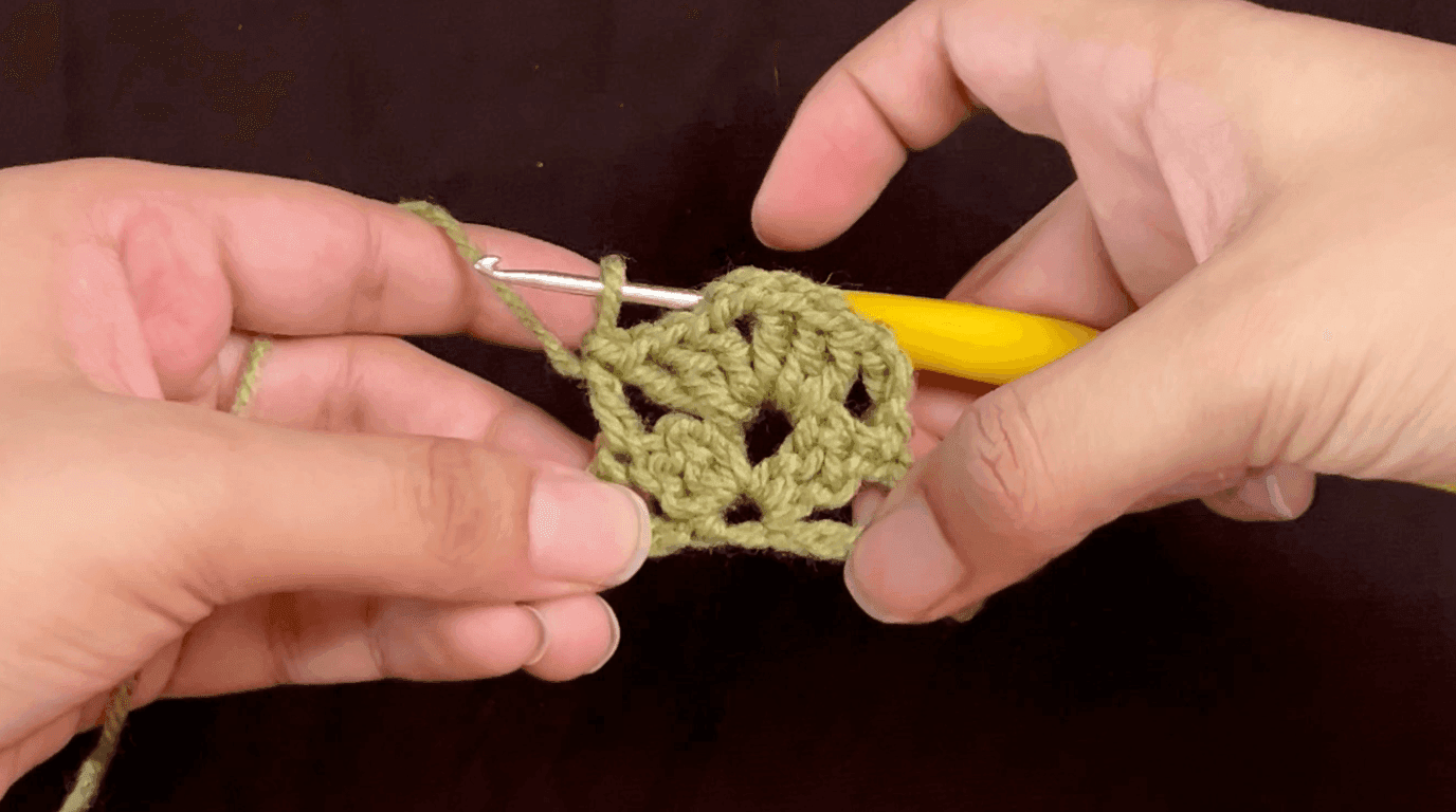 Hands working row 2 of a granny stripe bookmark, double crocheting into the double crochet stitch from the previous row
